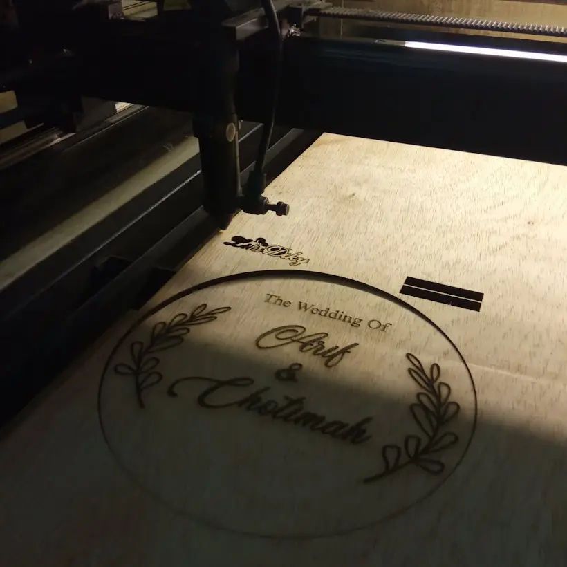Proses grafir laser tulisan The Wedding Of di papan plywood
